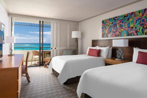 two beds in a hotel room with a view of the ocean at The Royal Hawaiian, A Luxury Collection Resort, Waikiki in Honolulu