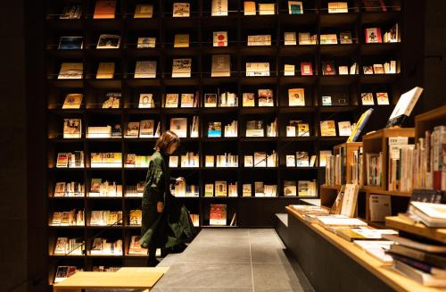 a woman standing in front of a book shelf at TUNE STAY KYOTO in Kyoto