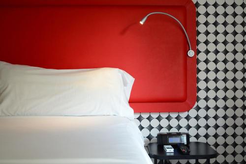 a bed with a red headboard and a table with a lamp at Velasco House in Buenos Aires