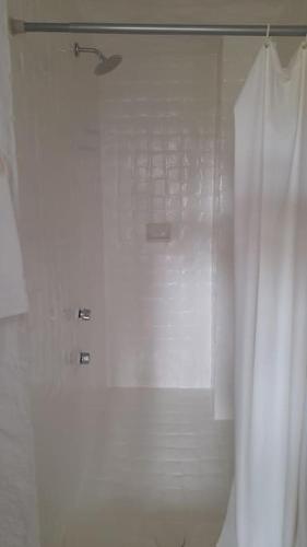a shower with a white curtain in a bathroom at Sol y Mar. Delfines in Ixtapa