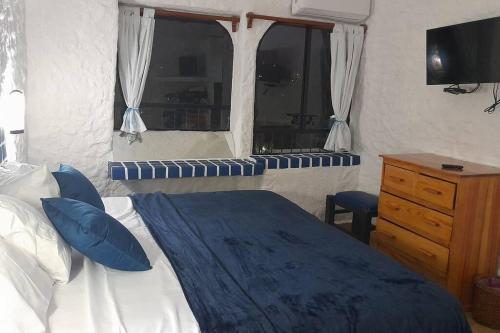 a bedroom with a bed with blue pillows and a window at Sol y Mar. Delfines in Ixtapa
