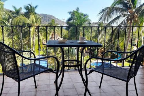 a table and chairs on a balcony with palm trees at Sol y Mar. Delfines in Ixtapa