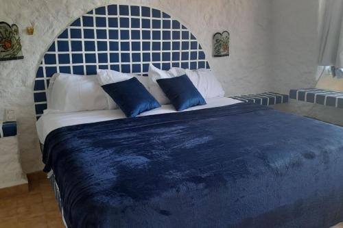 a bedroom with a large bed with blue and white pillows at Sol y Mar. Delfines in Ixtapa