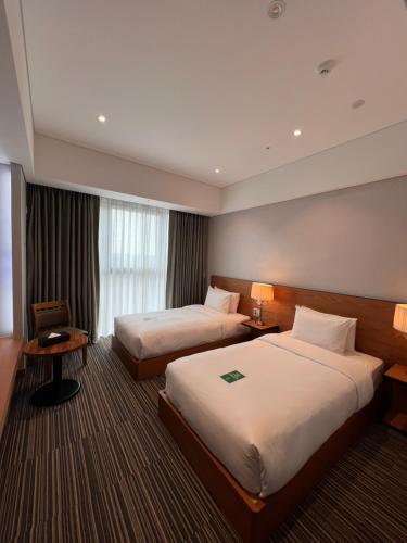 Hotel Tour Incheon Airport Hotel & Suites في انشيون: غرفة فندقية بسريرين ونافذة