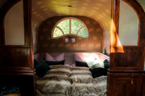 Schlafzimmer mit einem großen Bett und einem Fenster in der Unterkunft historischer Zirkuswagen inmitten der Natur in Fischach
