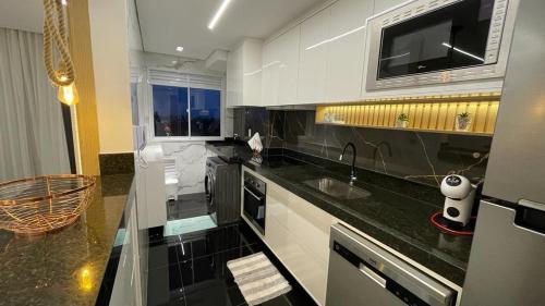 eine Küche mit einer Spüle und einer Mikrowelle in der Unterkunft Condomínio encantador de luxo in Goiânia