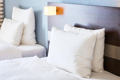 a bedroom with a bed with white pillows and a chair at ANA Crowne Plaza Kumamoto New Sky by IHG in Kumamoto