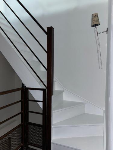 a staircase with white stairs and black railings at Maison climatisée avec stationnement et wifi in Bram