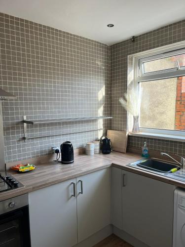 a kitchen with white cabinets and a sink and a window at 2 bed Central Cardiff Apartment - sleeps five! in Cardiff
