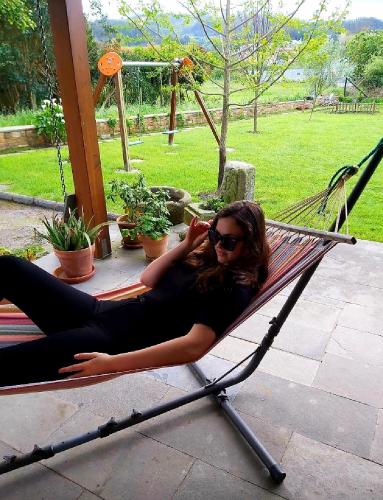 a woman laying on a hammock while talking on her cell phone at Casetón do Forno. in Lourenzá