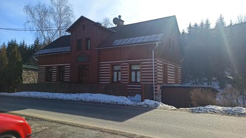 a large wooden house with a man on the roof at Maxova Bouda in Josefuv dul