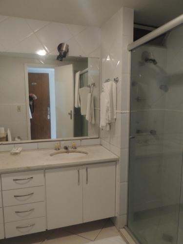 a bathroom with a sink and a shower with a mirror at Brasilia Apart Hotéis in Brasília