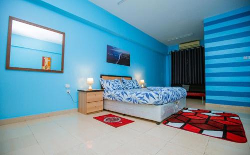 a bedroom with blue walls and a bed and a dresser at Queens Rentals - Studio Apartments - Village Walkway - Masaki - Dar es Salaam in Dar es Salaam