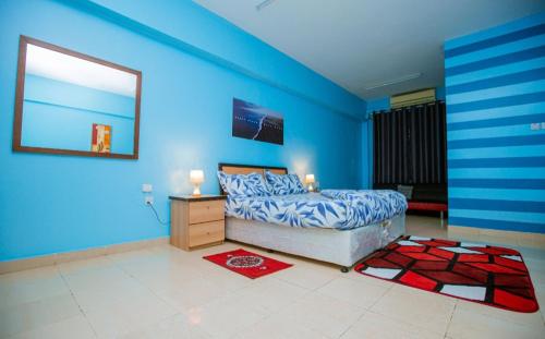 1 dormitorio con paredes azules, 1 cama y vestidor en Queens Rentals - Studio Apartments - Village Walkway - Masaki - Dar es Salaam, en Dar es Salaam