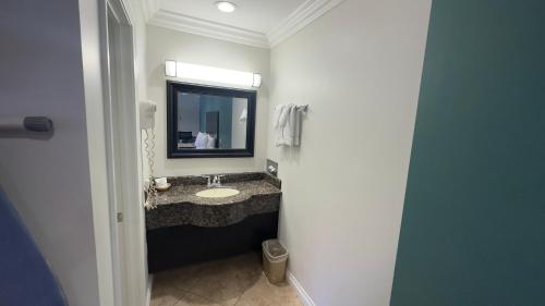 W łazience znajduje się umywalka i lustro. w obiekcie Garden Inn and Suites Glendora w mieście Glendora