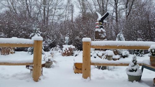 a snow covered garden with a bench and a fence at Long Holiday Motel in Gunnison