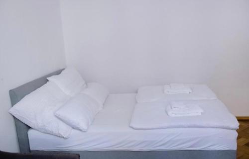 Una cama con sábanas blancas y almohadas. en Lorena’s Apartment, en Arad