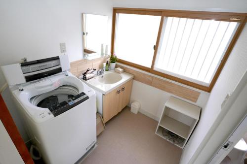 a small bathroom with a washing machine and a sink at ヒュッテ・ボーデン in Komoro