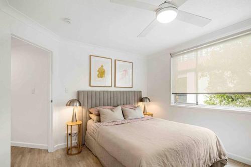 a white bedroom with a bed and a window at Blush on Broadbeach- beachside and pet friendly in Gold Coast