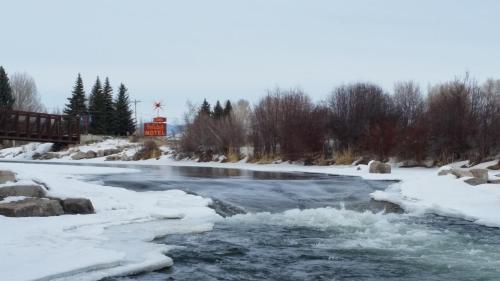 a river covered in snow with a windmill in the background at Long Holiday Motel in Gunnison