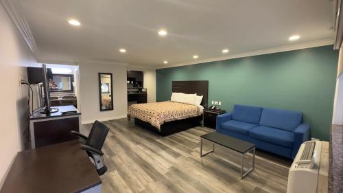 une chambre d'hôtel avec un lit et un canapé bleu dans l'établissement Garden Inn and Suites Glendora, à Glendora