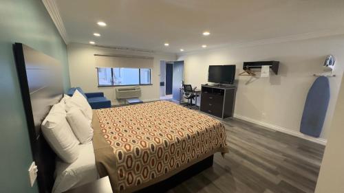 a hotel room with a bed and a television at Garden Inn and Suites Glendora in Glendora