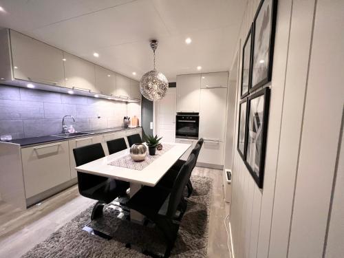 uma cozinha com uma mesa branca e cadeiras pretas em Lofoten and Vesterålen Kveldro em Myrland