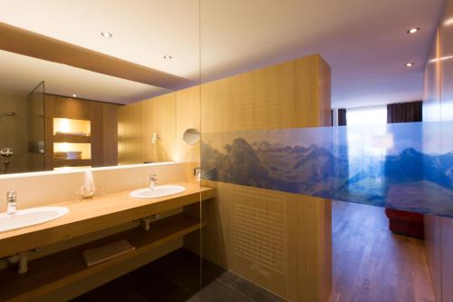 a bathroom with two sinks and a large mirror at Almhotel Hochhäderich in Riefensberg
