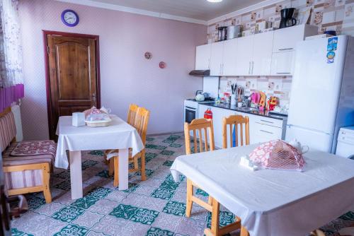a kitchen with two tables and chairs and a refrigerator at Guest House EtnoDom in Jalal-Abad