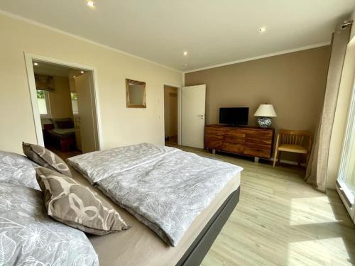 a bedroom with a bed and a dresser and a television at Ferienhaus Ankerplatz in Behrensdorf