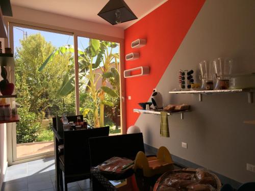 uma sala de jantar com uma parede laranja e uma janela em B&B Villa Magna Grecia em Lazzaro
