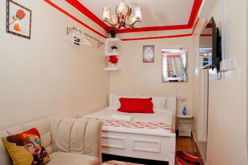 a small bedroom with a white bed with a red pillow at GEOLYN AIRBNB Naivasha in Naivasha