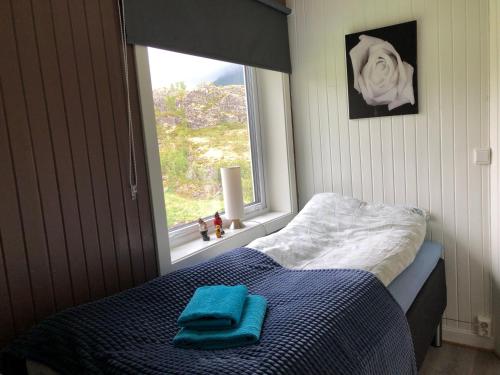 a bed with a blue blanket and a window at Lofoten and Vesterålen Kveldro in Myrland