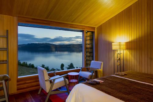 a bedroom with a large window with a view of a lake at Refugia Chiloé in San José