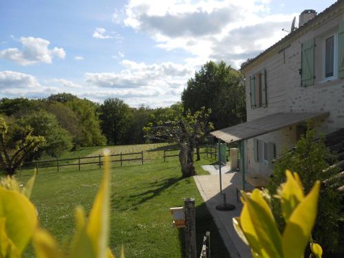 Blick auf ein Haus mit einem Feld und Bäumen in der Unterkunft Gîte des Gravets in Sigalens