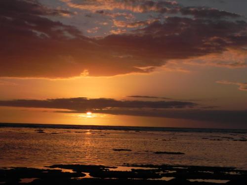 una puesta de sol sobre el océano con la puesta de sol en fleur de coton location saisonnière, en Grand Fond