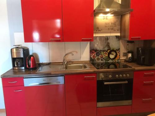 a red kitchen with a stove and a sink at Gemütliche Wohnung an der Nordseeküste 3 in Westerholt