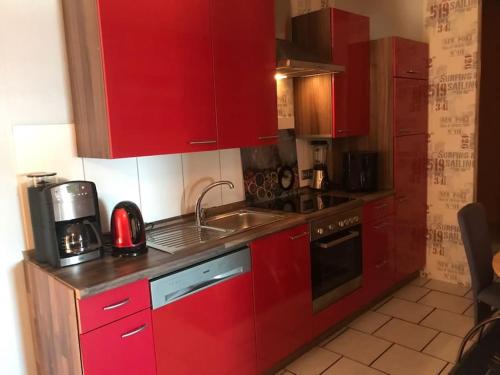 a kitchen with red cabinets and a sink at Gemütliche Wohnung an der Nordseeküste 3 in Westerholt