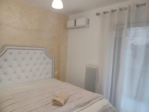 a bed with a white headboard and a window at Cozy Renovated Apartment in Athens