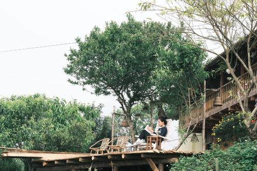 a man sitting on a bridge reading a book at La Beauté Sa Pa in Sa Pa