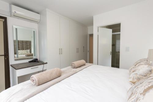 ein weißes Schlafzimmer mit einem großen weißen Bett mit Handtüchern darauf in der Unterkunft 67 The Shades - Luxury Apartment in Umhlanga - Airconditioning throughout and Inverter in Durban