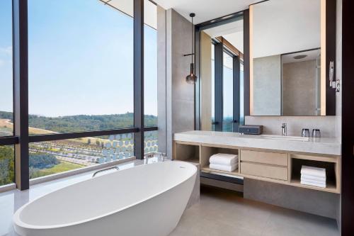 a bathroom with a tub and a large window at Courtyard by Marriott Qinhuangdao West in Qinhuangdao
