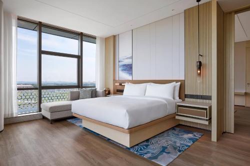 a bedroom with a bed and a couch and windows at Courtyard by Marriott Qinhuangdao West in Qinhuangdao