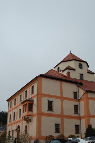 an orange and white building with cars parked in front of it at Hotel Garni Schloß Schönberg in Bad Brambach