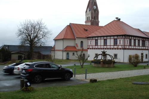 a black car parked in front of a building with a church at Hotel Garni Schloß Schönberg in Bad Brambach