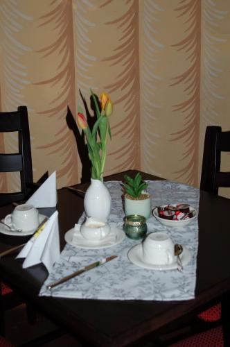 a table with a vase with flowers on it at Hotel Garni Schloß Schönberg in Bad Brambach