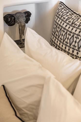 a close up of a bed with white pillows and an elephant statue at Helianthus Dream Homes in Oia