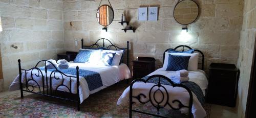 a bedroom with two beds and a mirror at Warda Accommodation in Xewkija
