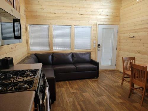 ein Wohnzimmer mit einem schwarzen Sofa und einem Herd in der Unterkunft 036 Tiny Home nr Grand Canyon South Rim Sleeps 8 in Valle