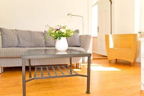una sala de estar con sofá y un jarrón de flores sobre una mesa en Villa Astrid, T2 Rostock, en Bansin